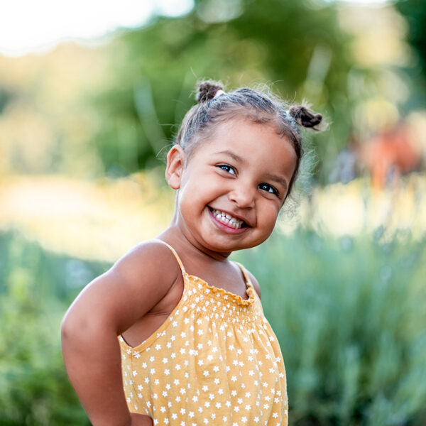 Portrait of a cute little cheerful mixed race girl in a yellow summer rummper.